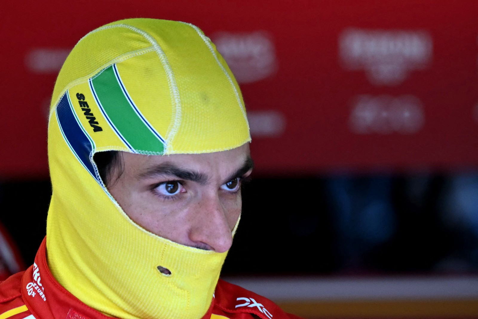 O piloto espanhol da Ferrari, Carlos Sainz, se prepara para a corrida usando uma balaclava com as cores da bandeira do Brasil para homenagear o falecido piloto brasileiro Ayrton Senna, nos boxes antes do Grande Prêmio de Fórmula 1 da Emilia Romagna, no Autódromo Enzo e Dino Ferrari em Imola — Foto: ANDREJ ISAKOVIC / AFP